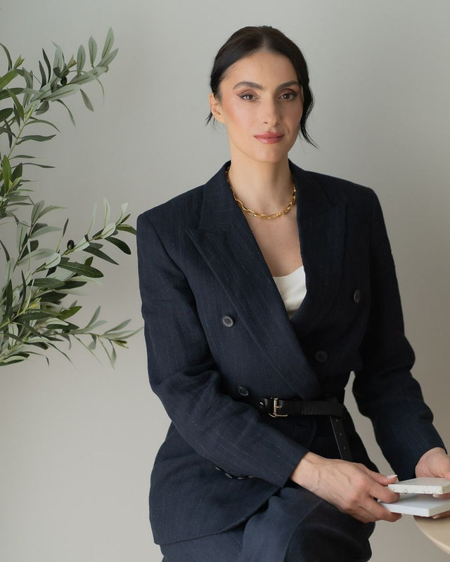 Madalina Aris, founder of Studio Sakaia, holding stone samples at a moodboard in the studio's Dubai office.