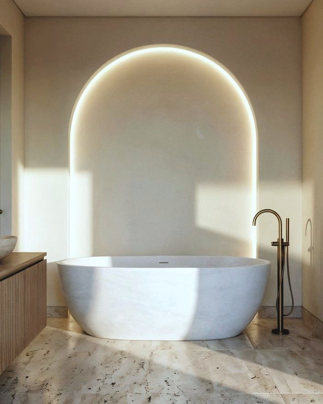 Bathroom design study: backlit arch niche behind a freestanding stone tub, brass floor mounted tap.