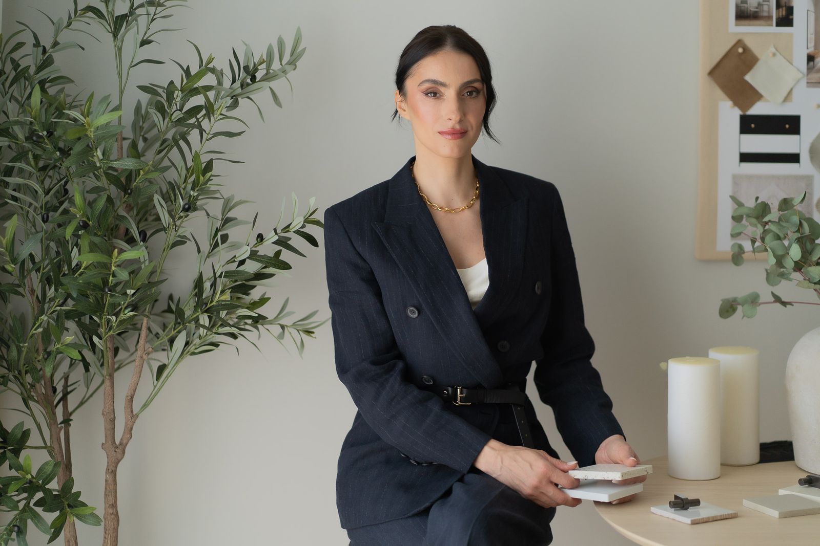 Madalina Aris, founder of Studio Sakaia, holding stone samples at a moodboard in the studio's Dubai office.