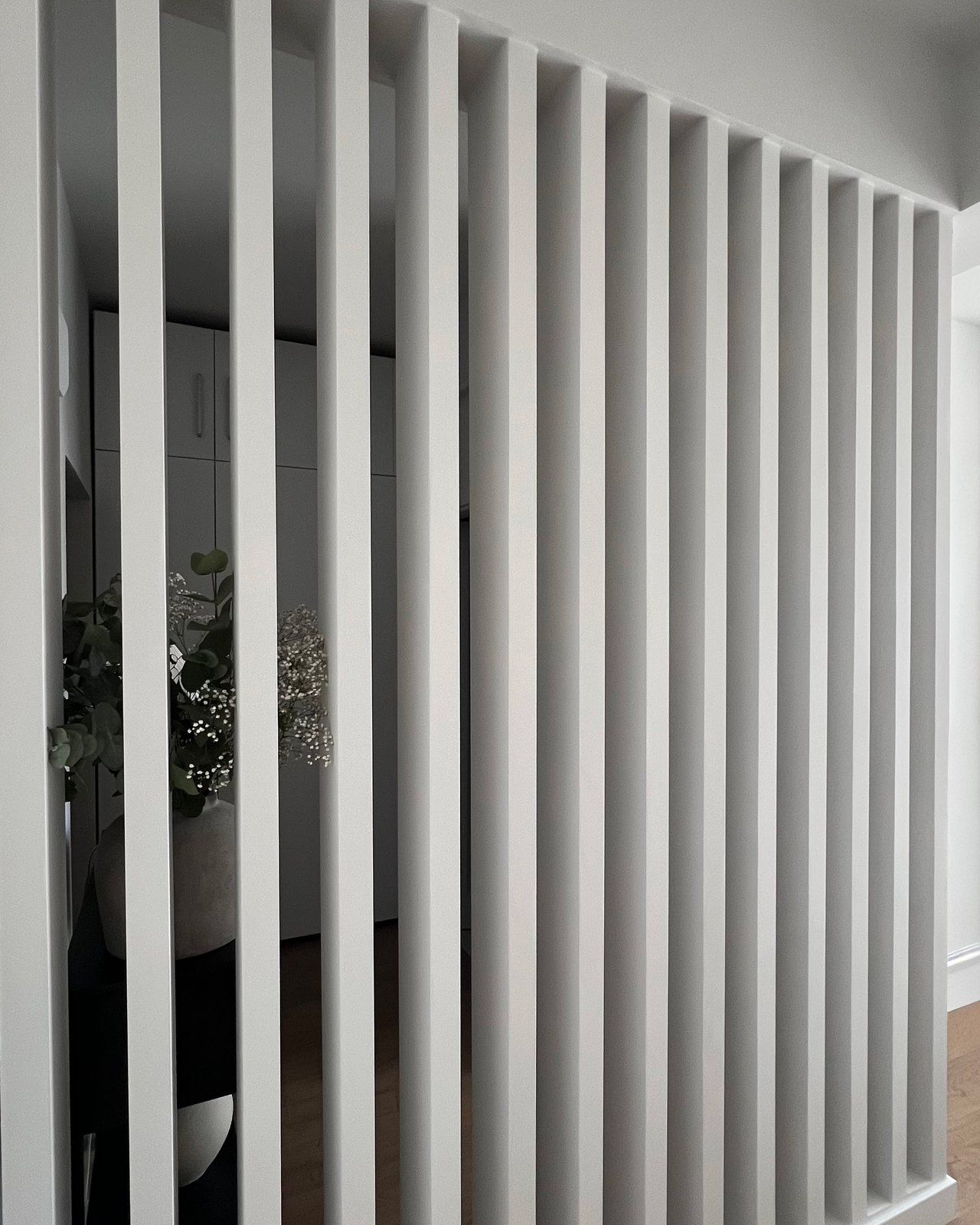 The finished slatted timber room divider seen straight on, whitewashed timber and daylight, Studio Sakaia, Dubai