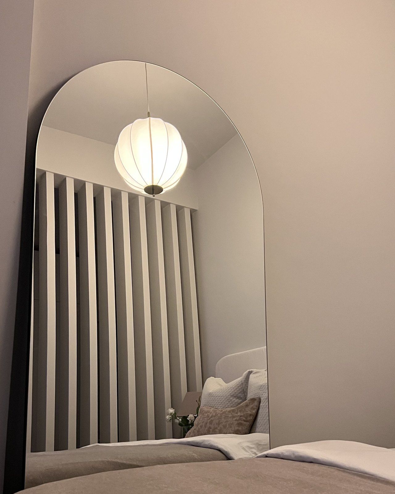 The finished room divider reflected in an arched mirror beside the styled bed, warm lamplight, Studio Sakaia, Dubai