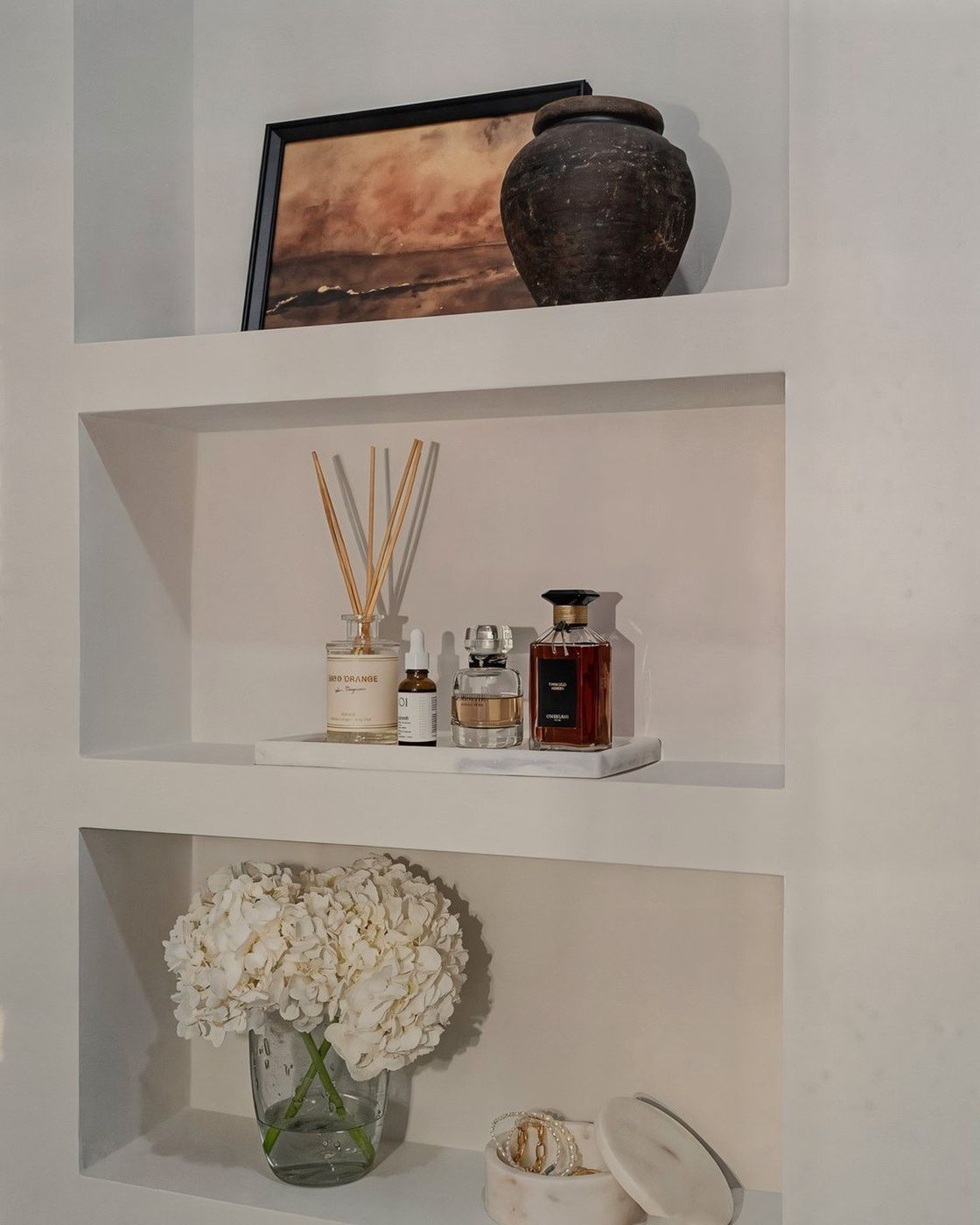 The finished wall niche fully styled with an antique pot, framed artwork, and diffuser, Studio Sakaia, Dubai