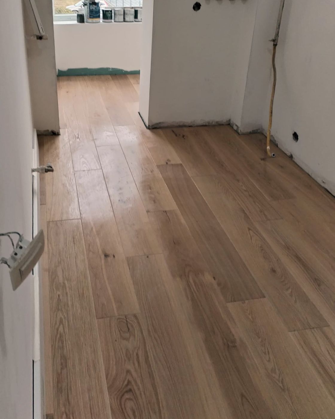 A finished engineered oak floor running down a hallway toward a bedroom, Studio Sakaia, Dubai