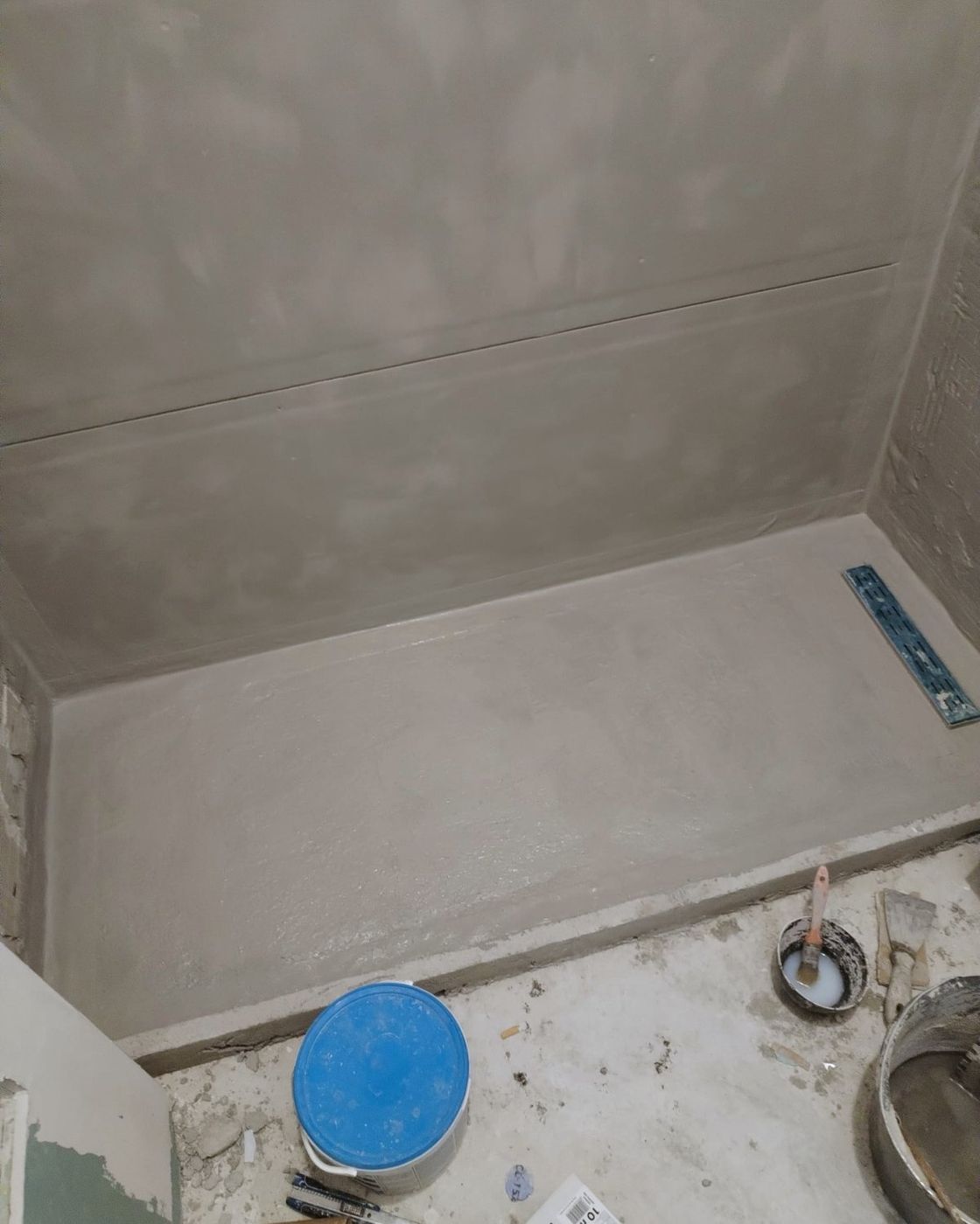 Grey waterproofing membrane over the shower floor and walls with the linear drain channel set in, Studio Sakaia, Dubai