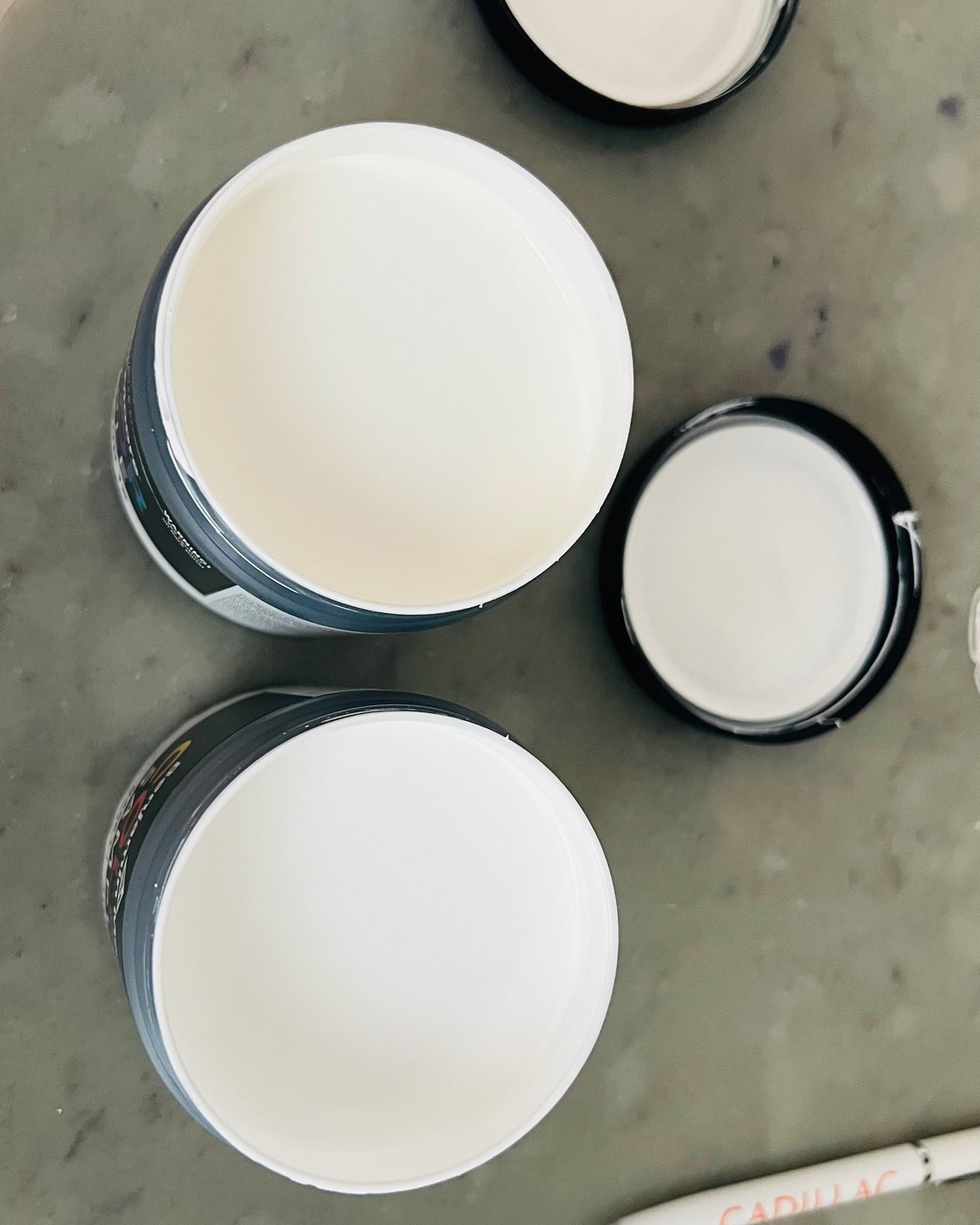 Open tins of white paint samples on a stone counter during Studio Sakaia's own Dubai renovation