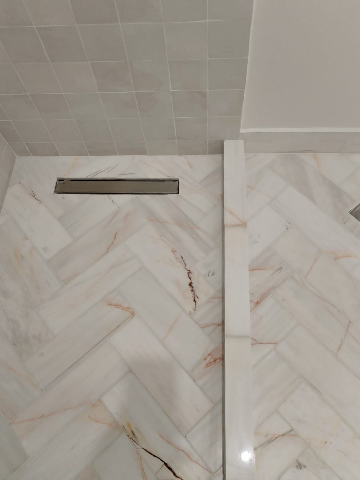 A shower area tiled in Marazzi Gesso zellige-look tile catching the light unevenly, brass fittings, from Studio Sakaia's own Dubai renovation