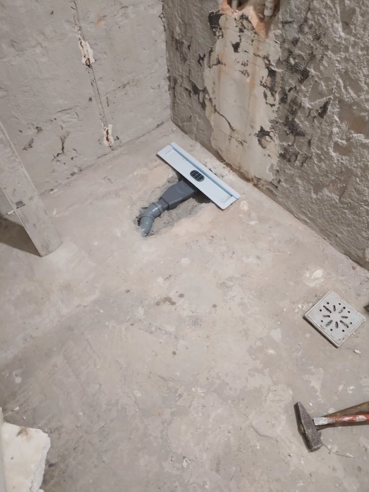 A drain in a screeded shower floor, the rough-in before any tile, Studio Sakaia, Dubai