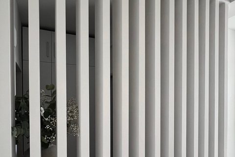 The finished slatted timber room divider seen straight on, whitewashed timber and daylight, Studio Sakaia, Dubai