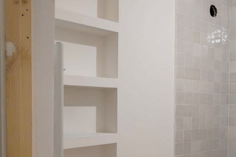 A staggered wall niche in plaster beside a tiled shower wall, before styling, from Studio Sakaia's own Dubai renovation
