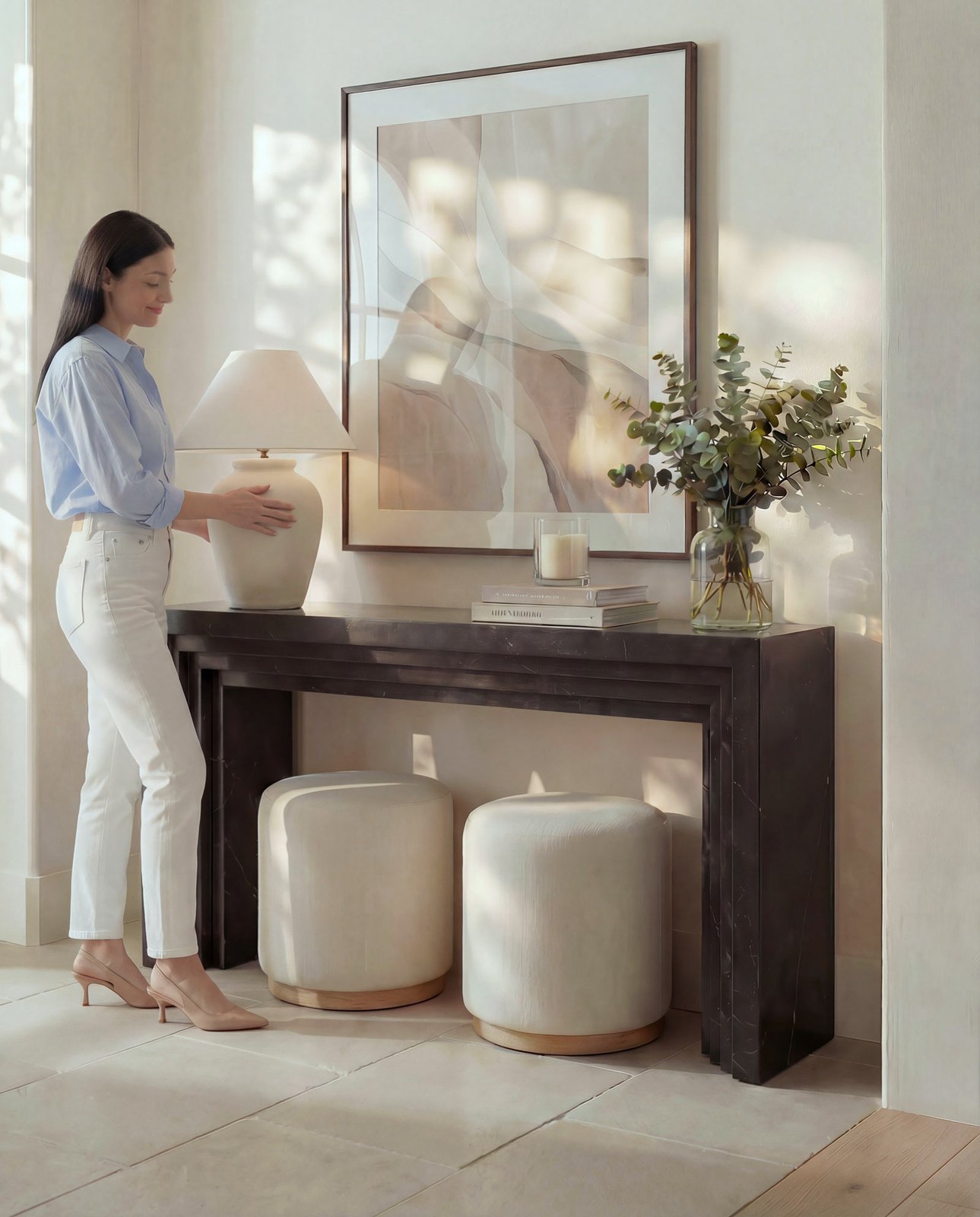 Jumeirah townhouse entry styled with a dark console, a pleated lamp, framed art and a pair of stools, Dubai