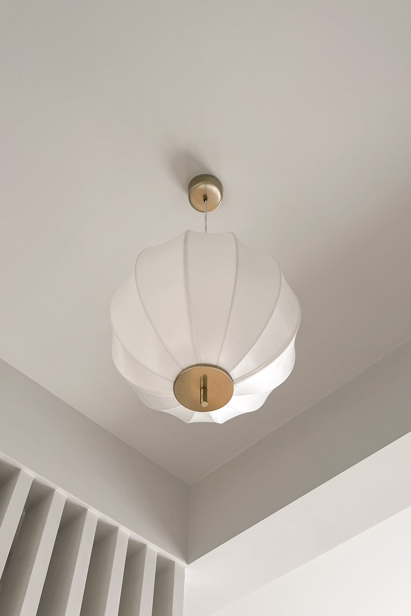 A pleated shell pendant with a brass fitting in the Studio 51 bedroom, Business Bay, Dubai