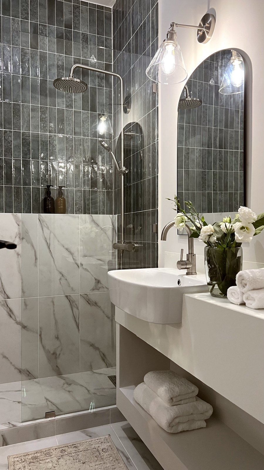 Studio 51 bathroom: a green zellige shower, Calacatta-look marble, a wall-hung basin and a tall arched mirror, Business Bay, Dubai